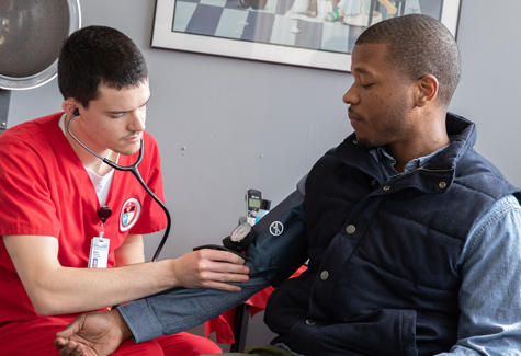male nursing student checks the blood pressure of an African American man